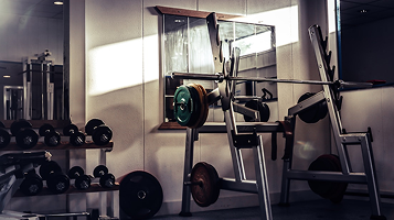 Weight benches and dumbbells lined up in an empty gym