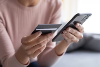 Credit Cards on UPI: FAQs - Women holding credit card and cellphone - IDFC FIRST Bank